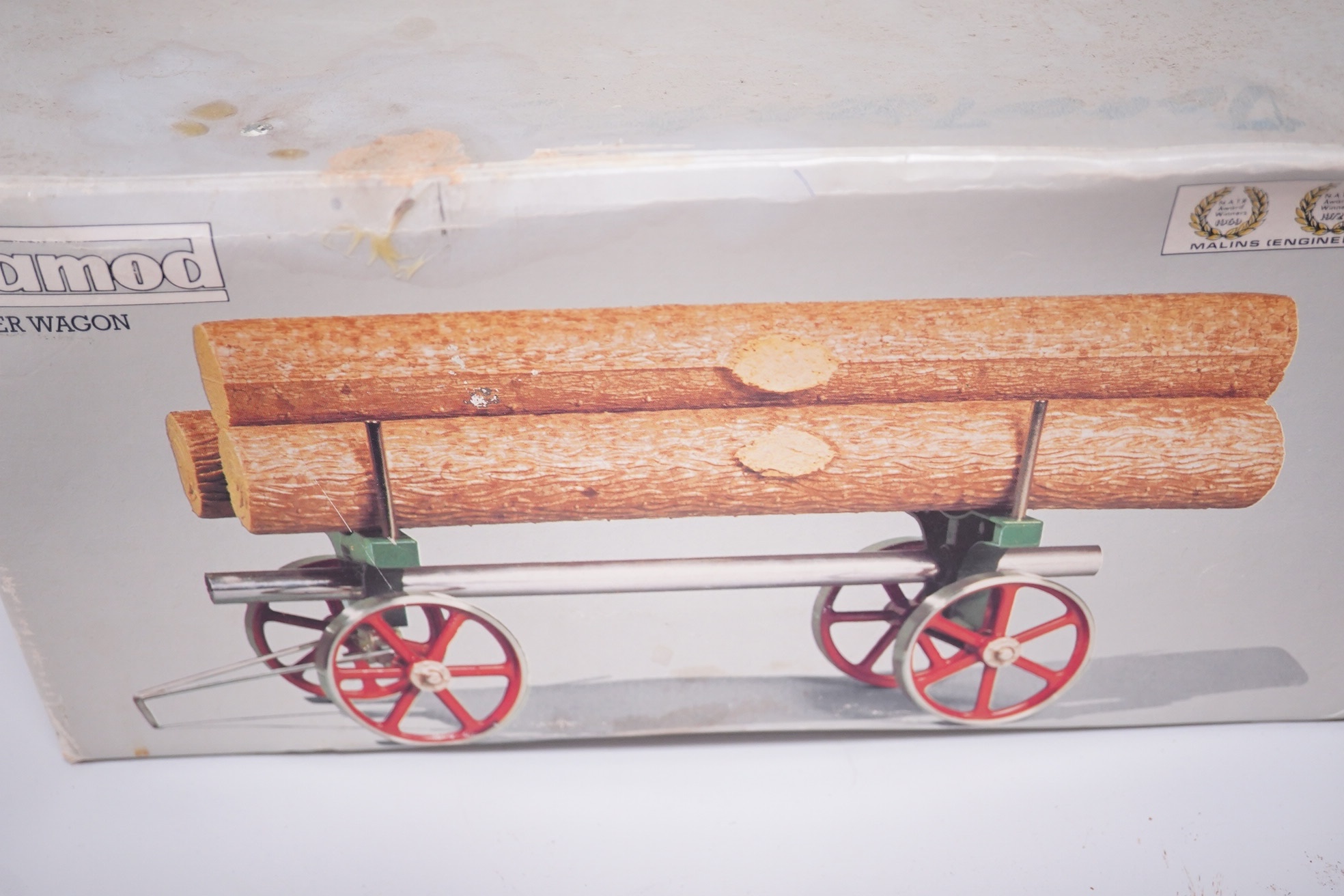 A boxed Mamod TE-1A live steam traction engine and lumber wagon. Condition - poor to fair, there is corrosion to the exposed aluminium and other metal parts.